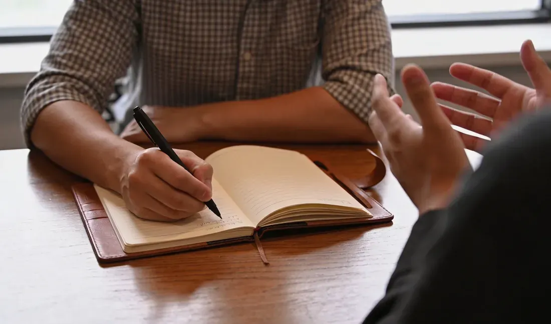 Une personne écrit dans un carnet pendant une discussion